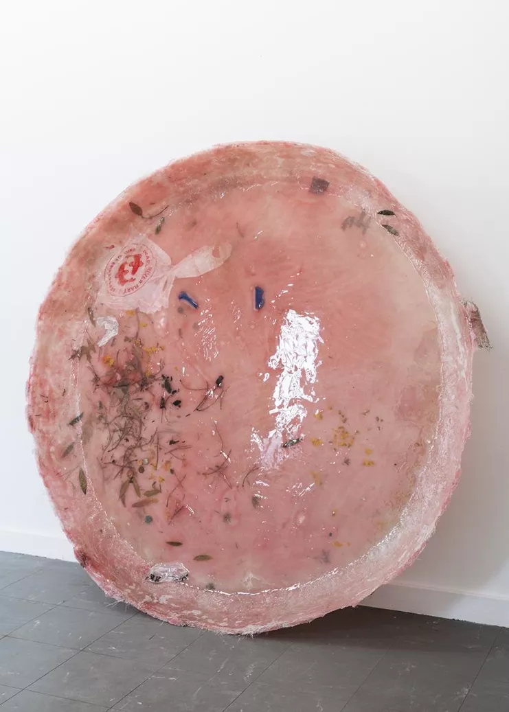 Cecilie Skov - «Våd af dug», 2019. Epoxy resin, glass fiber, plastic bag, leaves, flowers, straw, salt, sugar, fennel seeds, alu folio, tape, wax, coins, pigment. Ø: 130 cm.