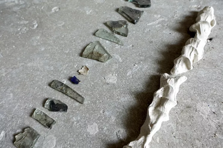 Εσμεράλδα Μομφερράτου, «Traces from the imaginary grave of Esme and Esmee», Γύψος, λιωμένο γυαλί, πετραδάκια, στερεοποιημένο χώμα, φρονιμίτες σε σφραγισμένη σακούλα, γύψινη οδοντοστοιχία, πηλός, κελύφη σαλιγκαριών, σκελετός αχινού, φλοιός δέντρου, 190x60x23 εκ., 2021
