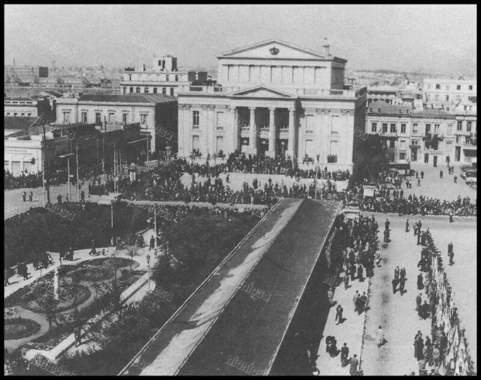 130 χρόνια Δημοτικό Θέατρο Πειραιά 1950-Άποψη του Δημοτικού Θεάτρου, από την εκκλησία του Αγίου Κωνσταντίνου, σε μέρα παρέλασης. Γύρω στα 1950. Από το βιβλίο του Νίκου Αξαρλή